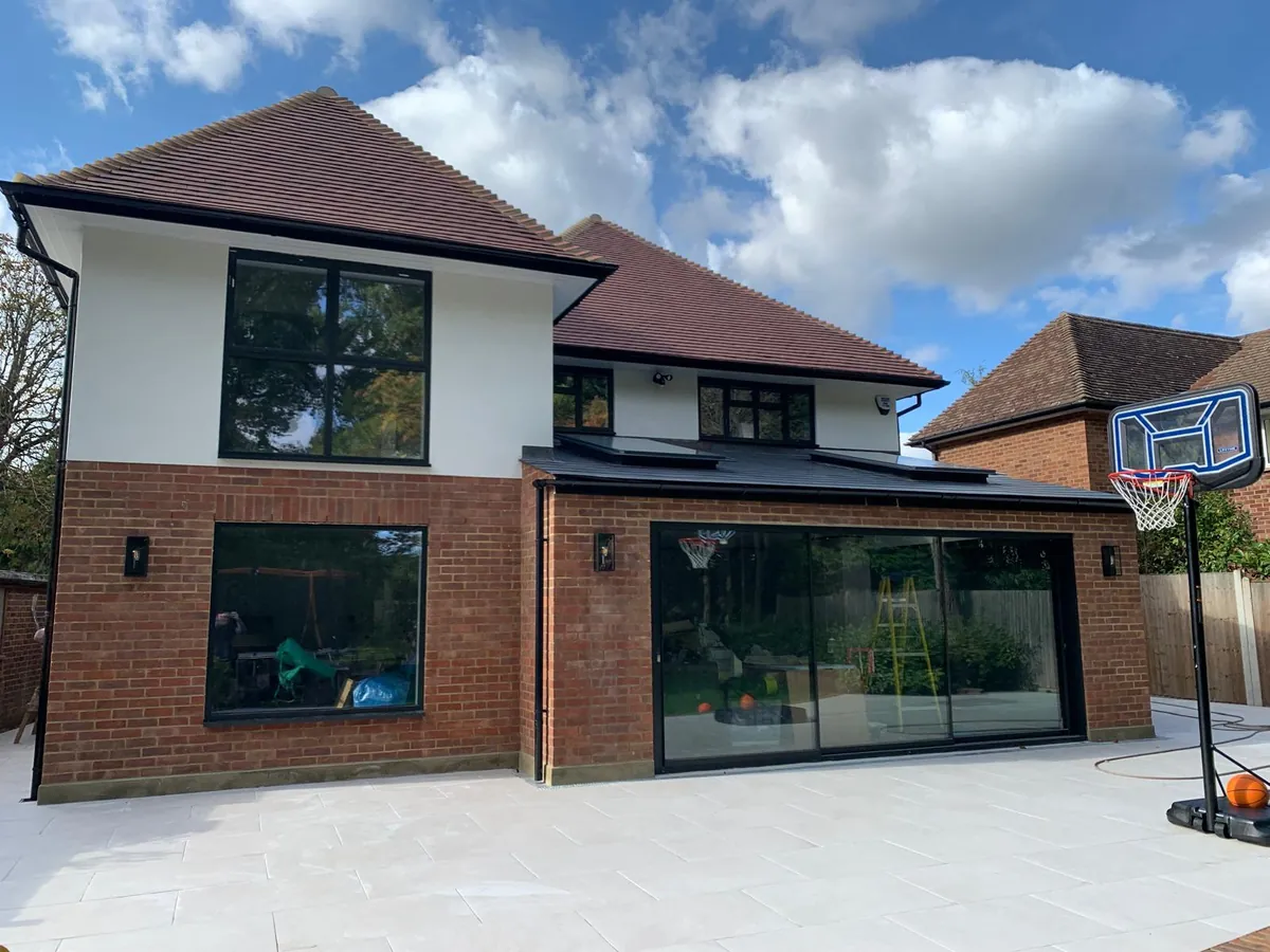Three-panel Cor Vision sliding doors with black aluminium windows on the rear of a newly built brick and render house