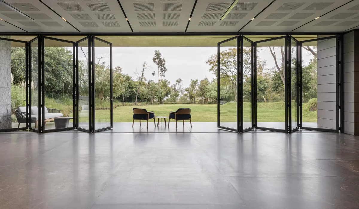 UniFOLD HI black bifold doors folded back on both sides of a wide opening onto a lawn